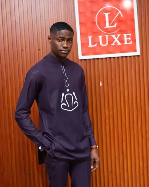 Devant l'enseigne rouge Luxe de la boutique